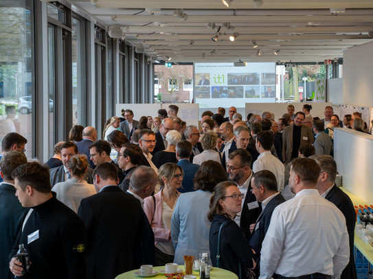 Menschen stehen im Foyer eines Gebäudes und unterhalten sich.