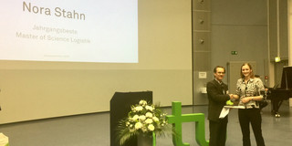 Nora Stahn und Prof. Mosler stehen im Audimax der Technischen Universität Dortmund