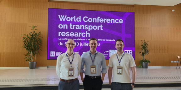 Clemens Balke, Marius Dellbrügge und Janis Purk stehen vor einer großen Anzeige, die auf die WCTR 2026 verweist.