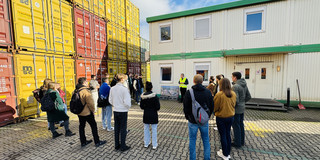 Studierende schauen zu einem Mitarbeiter des Container Terminals, der einen Vortrag hält. 