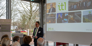 Professor Uwe Clausen steht vor einer Leinwand und spricht vor Publikum