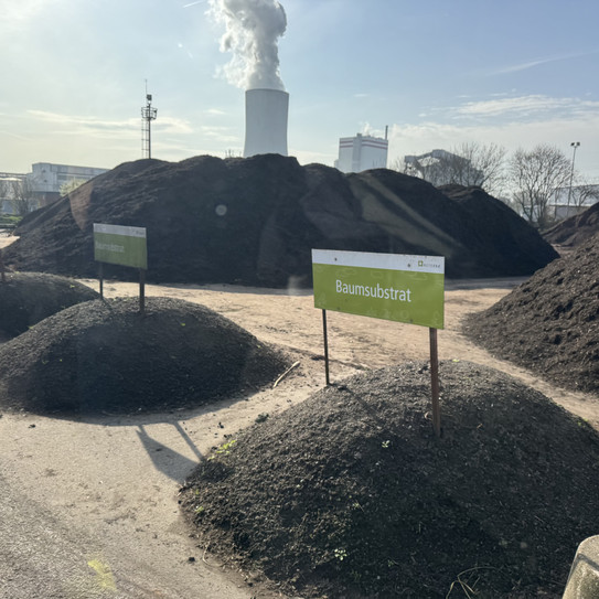 Mehrere Haufen unterschiedlicher Materialien liegen auf einem Platz mit Schildern drin