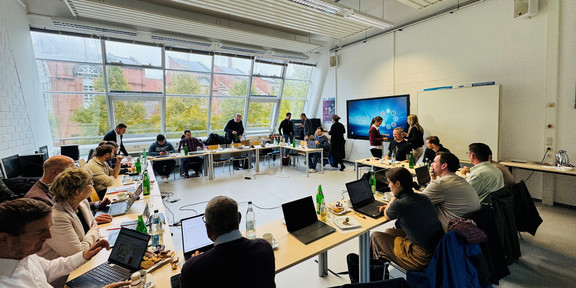 Menschen sitzen in einem Konferenzraum und unterhalten sich.