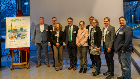 Alles Redner des Abends posieren vor einer Leinwand für ein Gruppenfoto