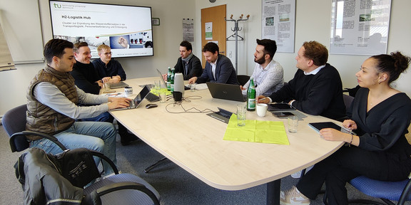 Die Arbeitsgruppe sitzt an einem Tisch und spricht miteinander