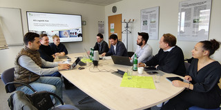 Die Arbeitsgruppe sitzt an einem Tisch und spricht miteinander