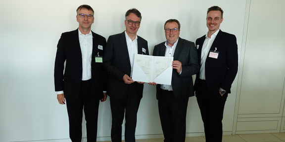 Professor Clausen, Marius Dellbrügge, Christian Krüger und Oliver Krischer halten den Förderbescheid