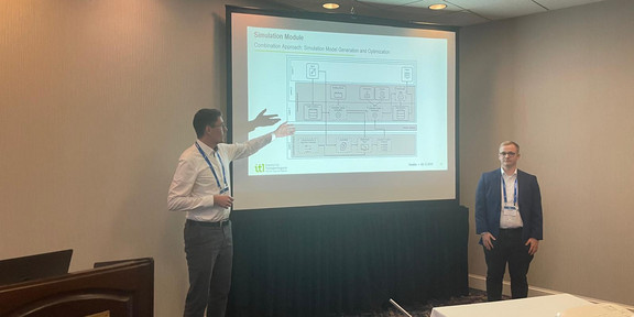 Herr Jurgeleit und Herr Buhle vor einer Präsentationstafel. Herr Jurgeleit zeigt auf das Bild.