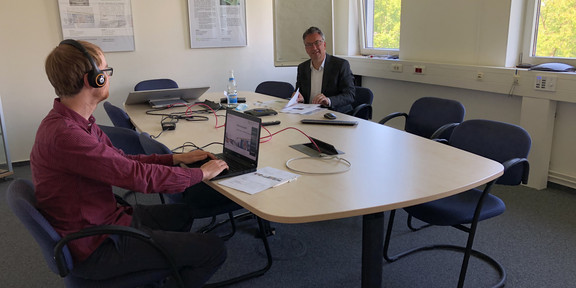 Prof. Uwe Clausen und Nicolas Kämmerling sitzen mit Abstand an einem Tisch.