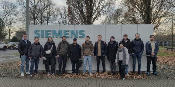 Professor Karch mit den Studierenden vor dem Siemens Firmenschild im Außenbereich