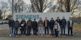 Professor Karch mit den Studierenden vor dem Siemens Firmenschild im Außenbereich