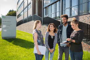 Vier Studierende stehen vor dem neu errichteten Physikgebäude.